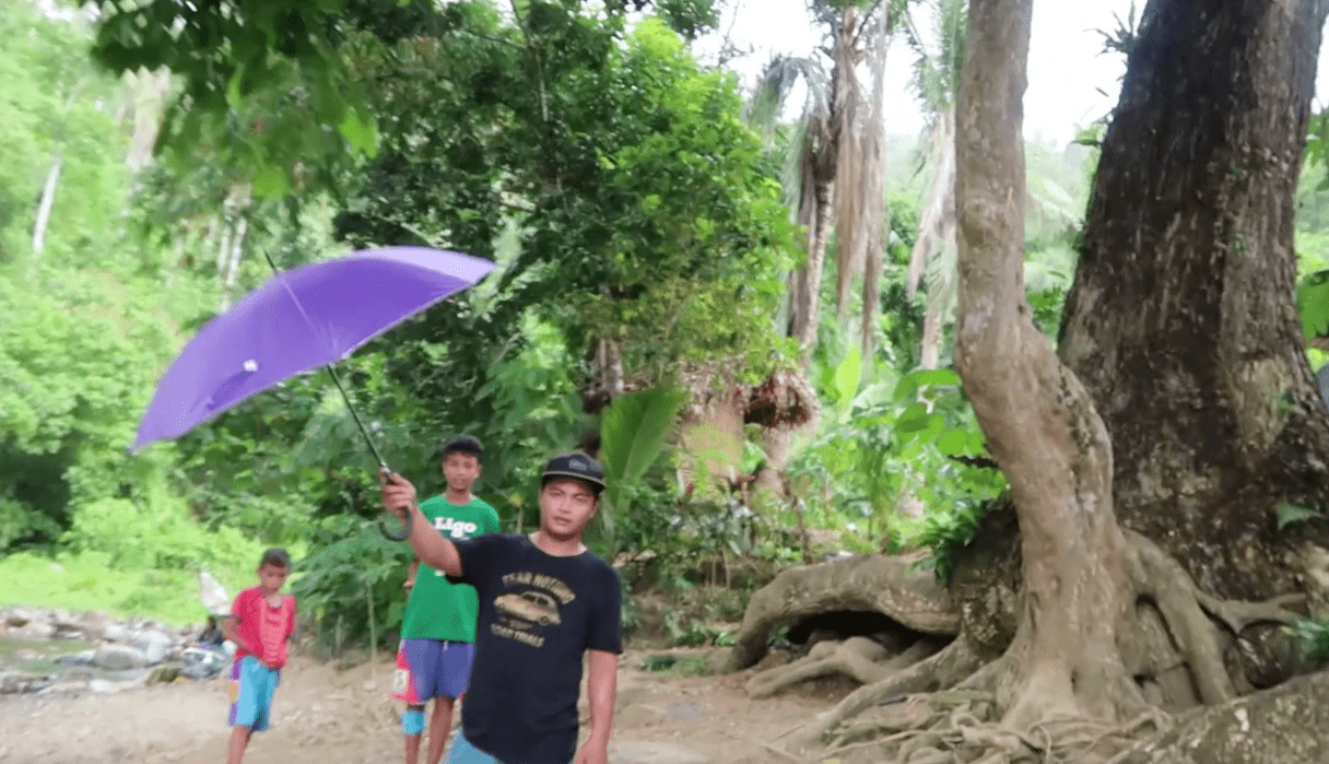 hospitable filipino young man holding umbrella for approacing foreigner in catanduanes province philippines